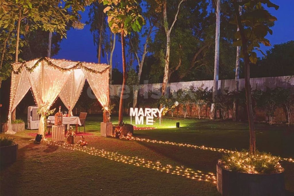 romantic proposal idea for Valentine's day celebration featuring a cabana themed candlelight dinner with Marry Me LED letters 
