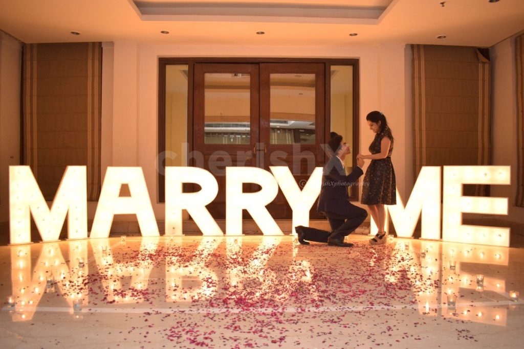 Proposal idea for Valentine's day in 2024 featuring giant Marry Me LED letters and rose petals 