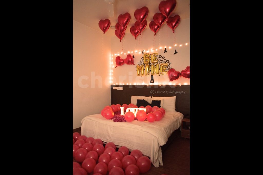 Valentine's day decorations in room featuring heart shaped foil balloons, BE MINE foil balloons, and red balloons