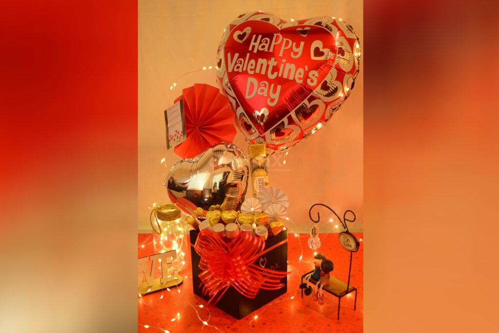 Valentine's day gift box featuring a silver heart shaped foil balloon, red heart shaped foil balloons, and chocolates