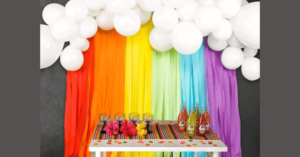 Rainbow party theme decoration with white balloons and multi-colored ribbons. 