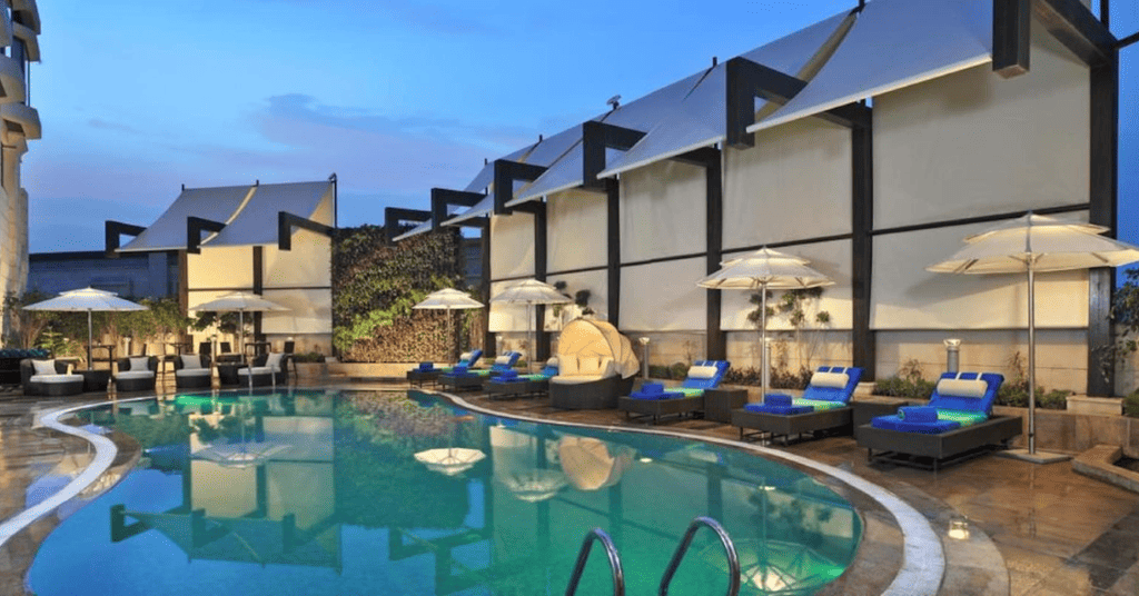 The Radisson Blu, Sohna for a perfect staycation in Delhi NCR with a outdoor pool area and relaxing seats. 
