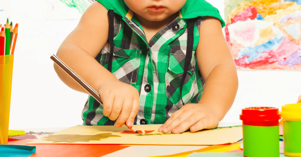 A kid scribbling on paper with a pencil. 