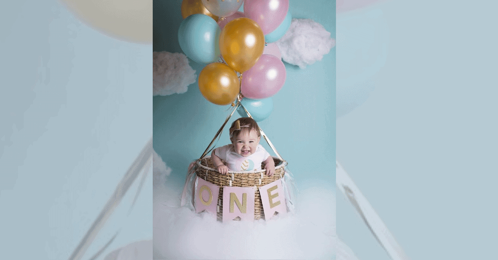one of the sweet photo ideas for 1st birthday where baby is inside the jute basket and it's adorned with balloons. 