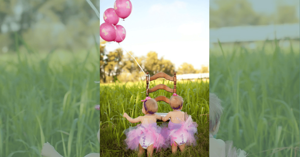 twin baby girl first birthday photoshoot with pink balloons. 