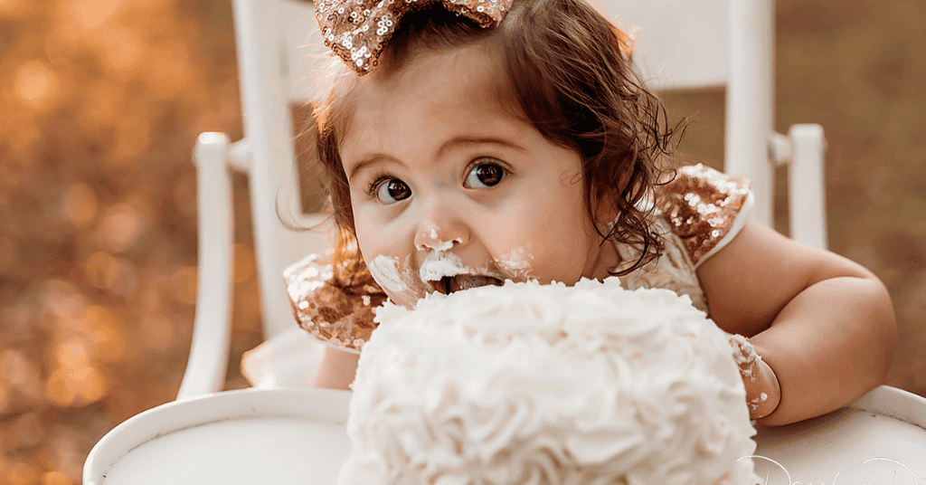 Delightful 1st birthday cake smash: Child enjoying fondant cake, pure happiness captured on her 1st birthday photoshoot.