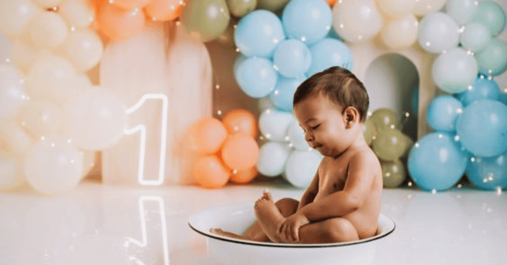 Sweet birthday photoshoot with pastel balloons: Child in a charming bath tub, '1' neon digit.