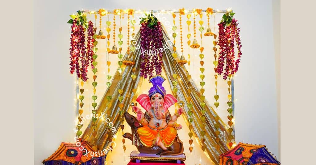 Shimmer Golden Theme Ganpati Decorations with artificial pink flowers and ornate bells. 