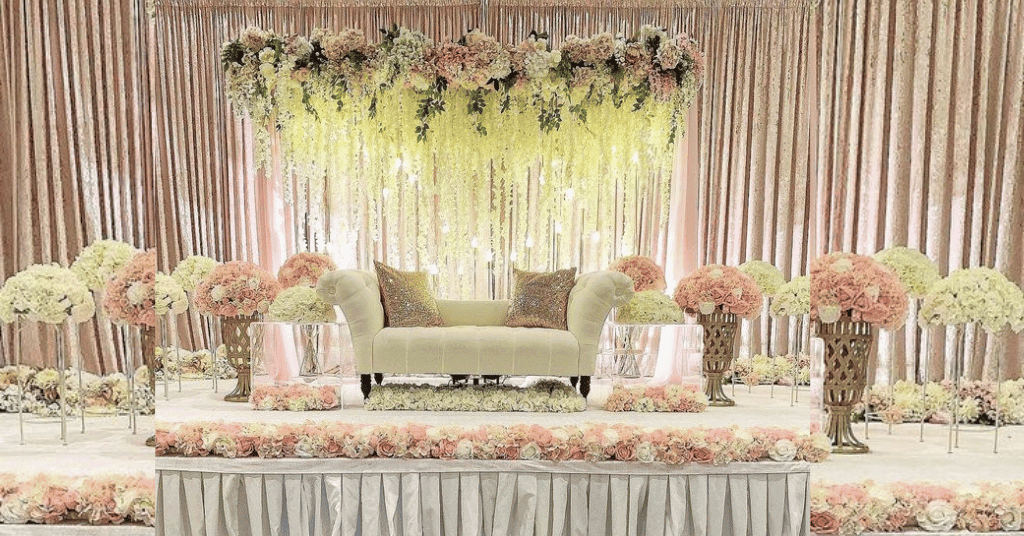 A Whimsical Nude Shade Engagement Decoration With Pink & White Flowers & A Pink Curtain Backdrop 