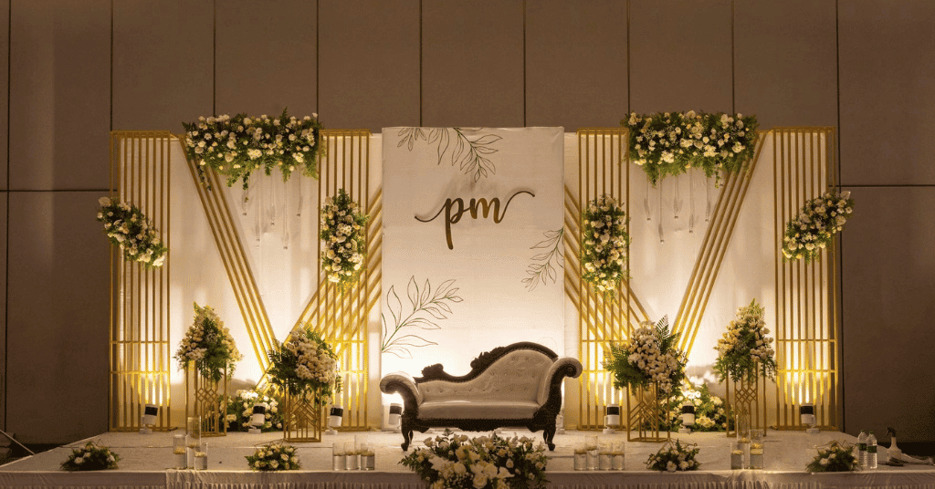A Gold & White Stage Backdrop with white flower bouquets 