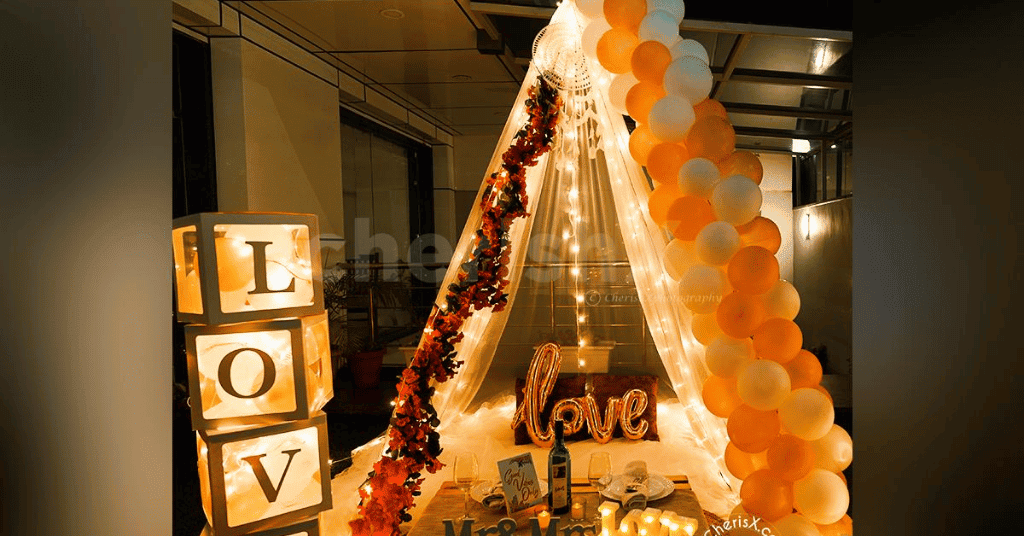  Terrace Decoration Idea that features a romantic boho Love canopy draped with a fabric and white and orange balloons 
