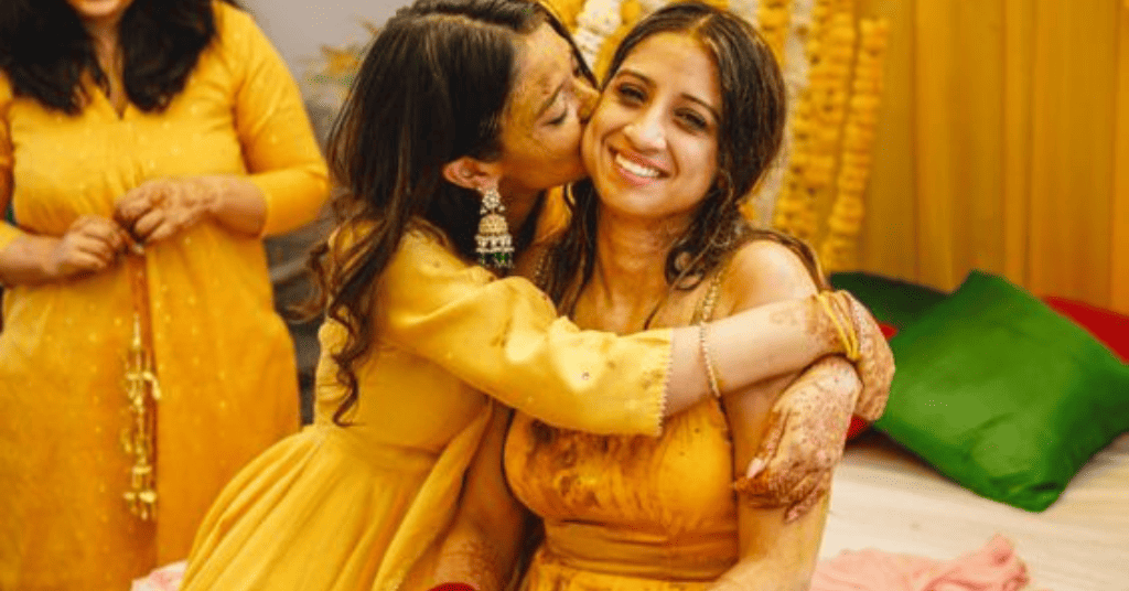 friend kissing the bride to be on her cheeks for a Haldi photo shoot idea 
